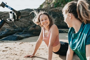 a couple of women sitting on top of a sandy beach