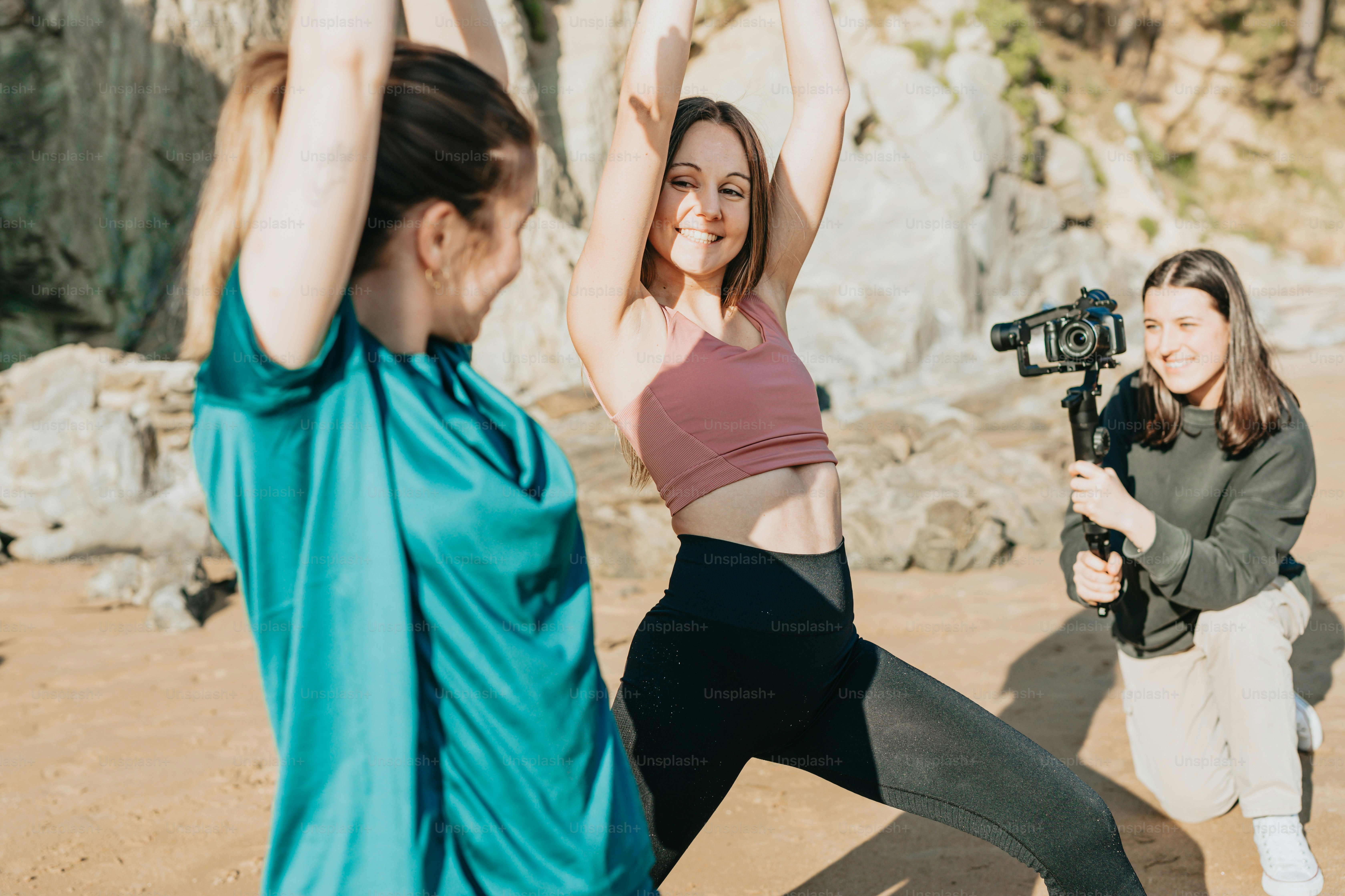 two women are doing yoga on the beach