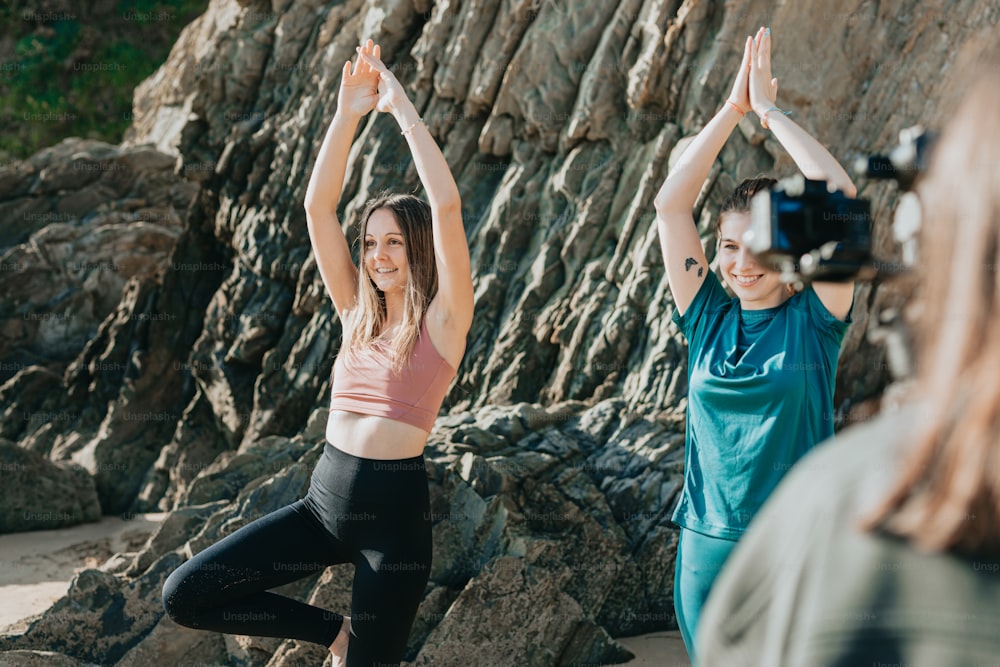 two women doing yoga on a rocky beach