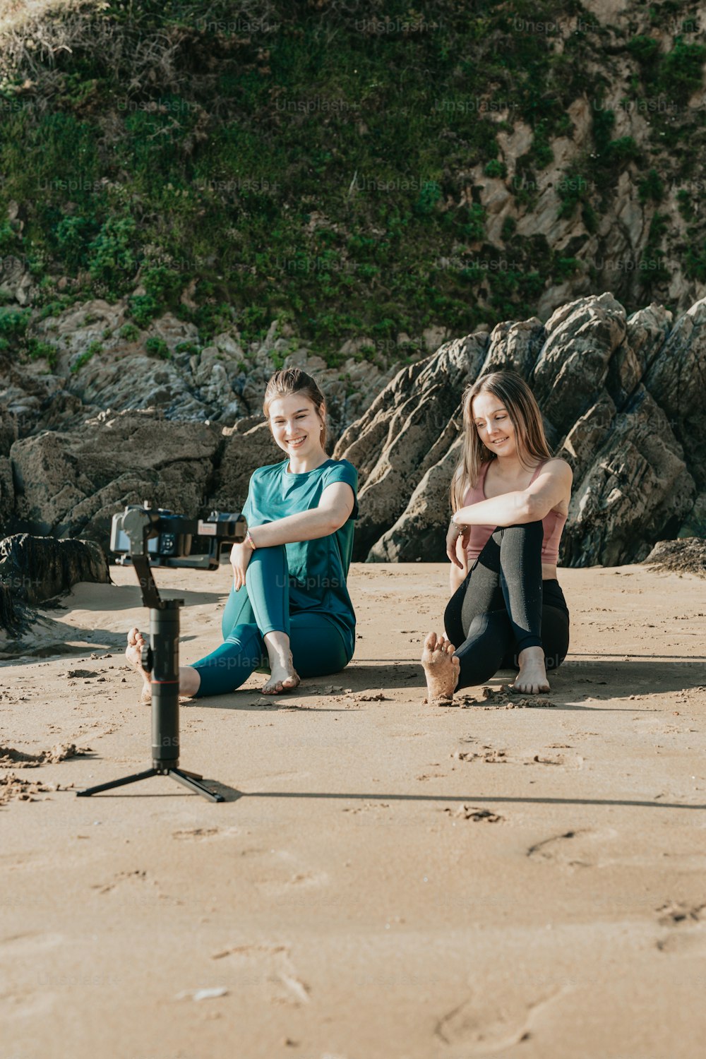 Un couple de filles assises au sommet d’une plage de sable