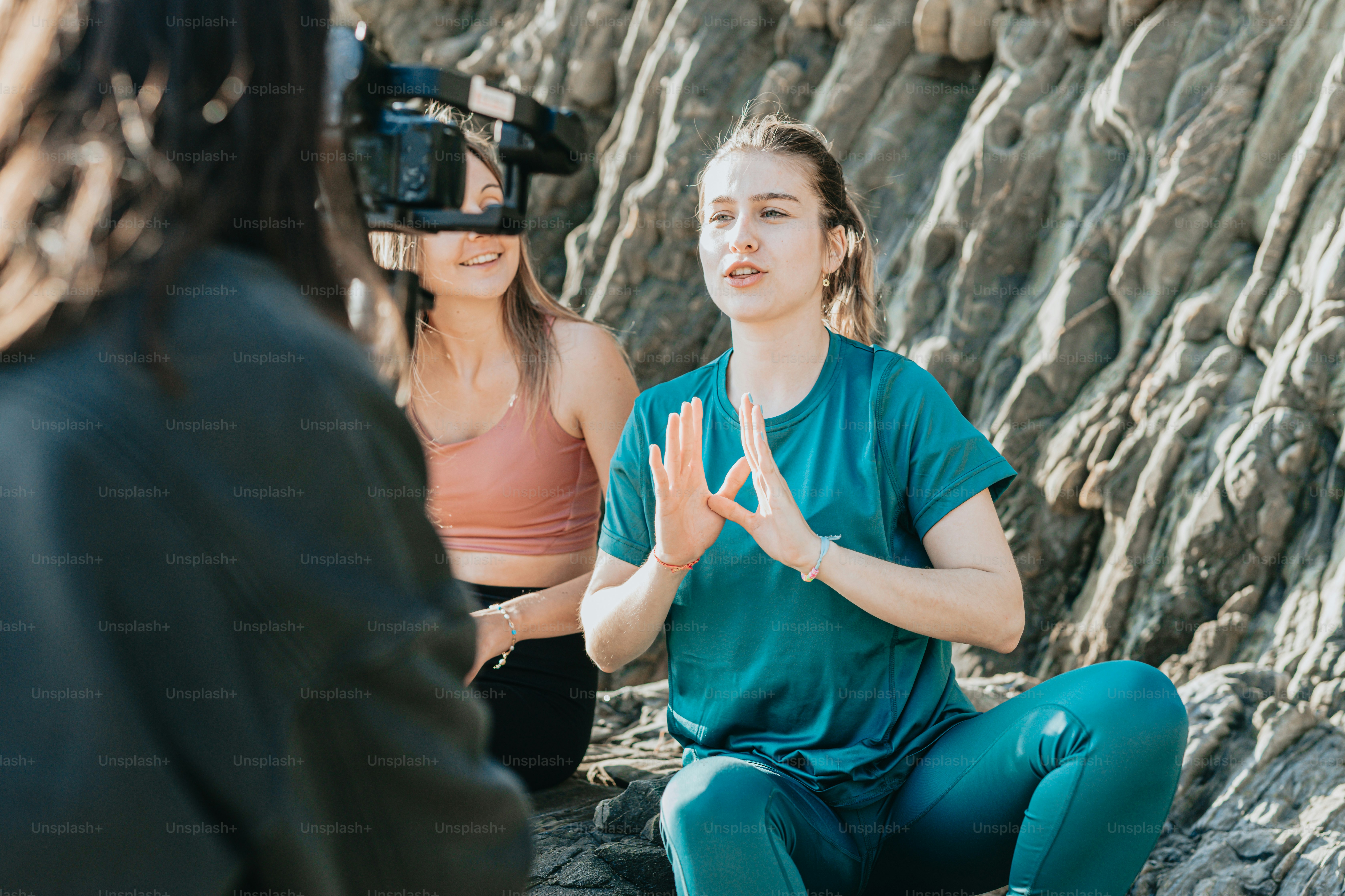 a woman sitting on a rock with a camera in front of her