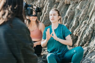カメラを前にして岩の上に座っている女性