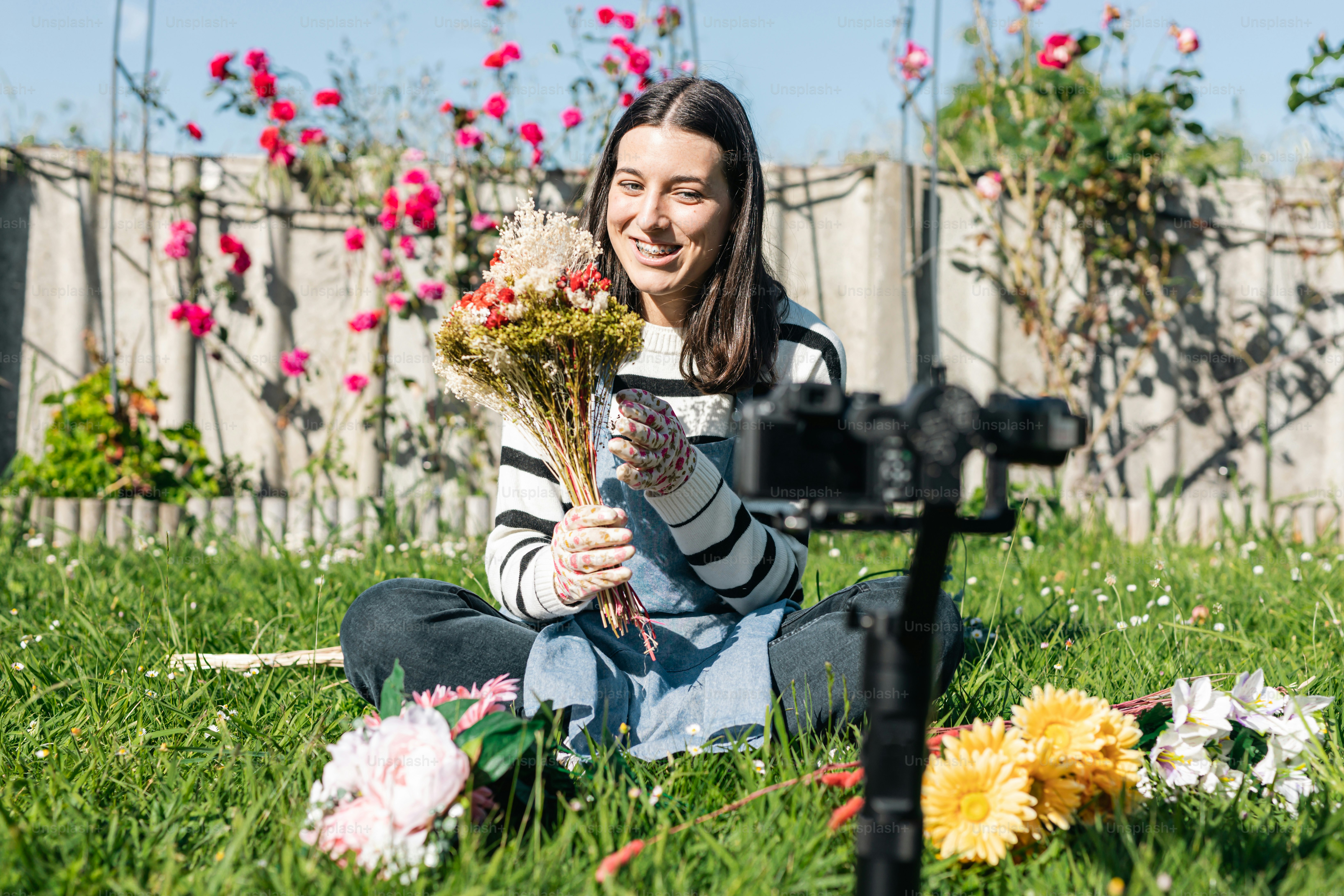 uma mulher sentada na grama segurando um buquê de flores