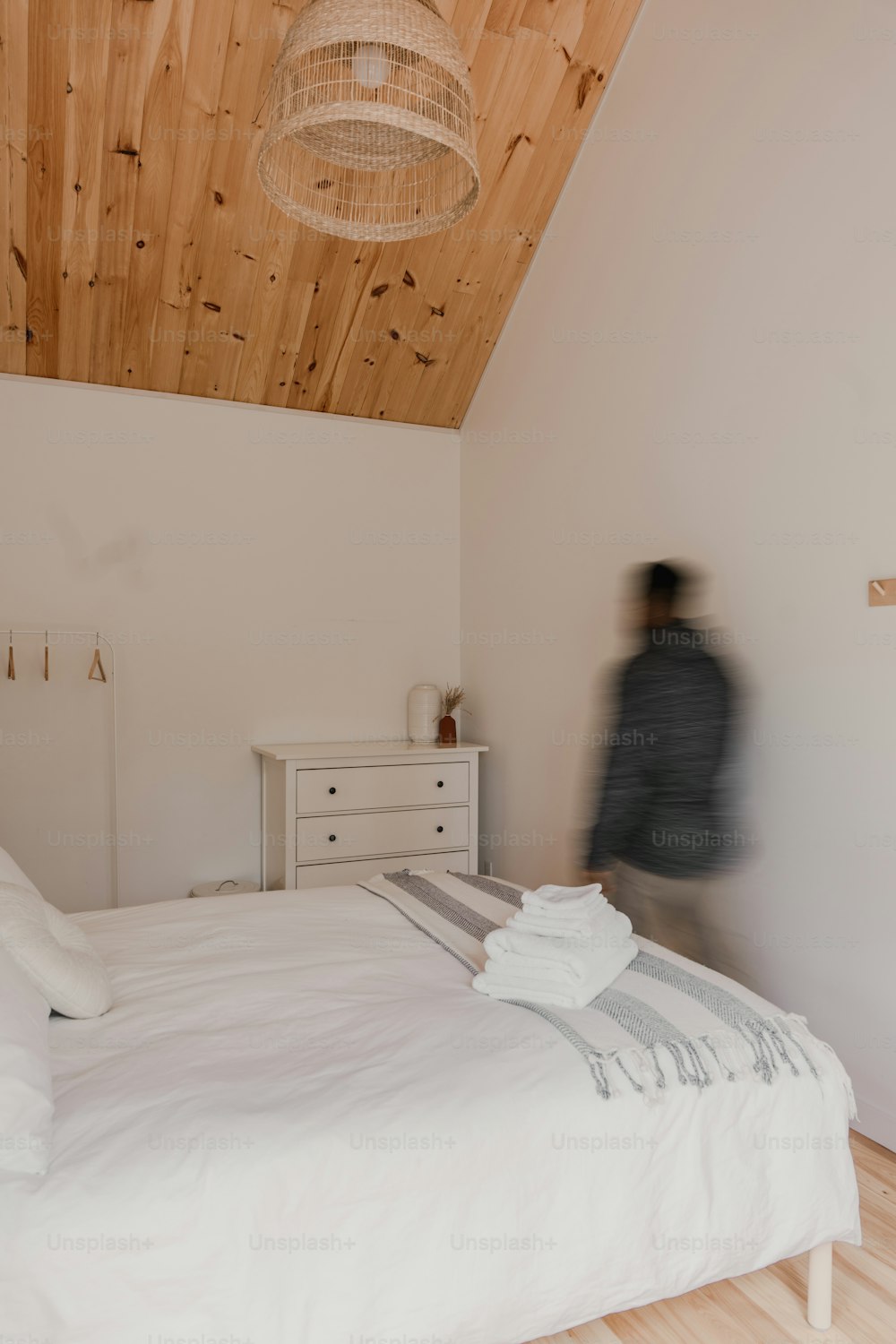 a person standing in a bedroom next to a bed