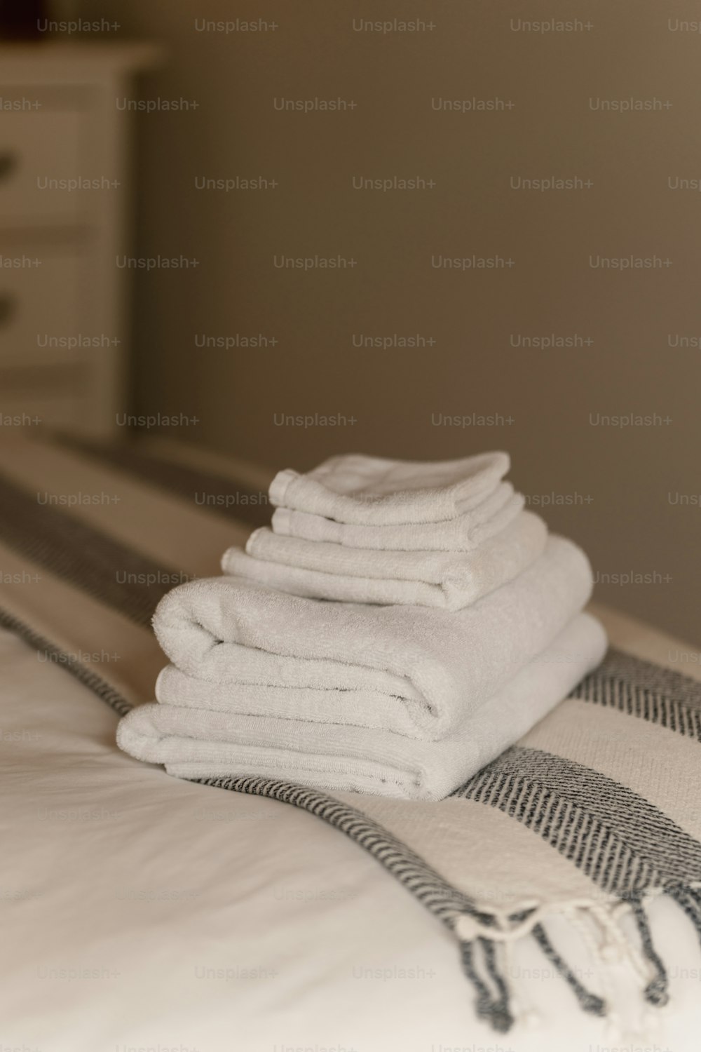 a stack of folded towels sitting on top of a bed