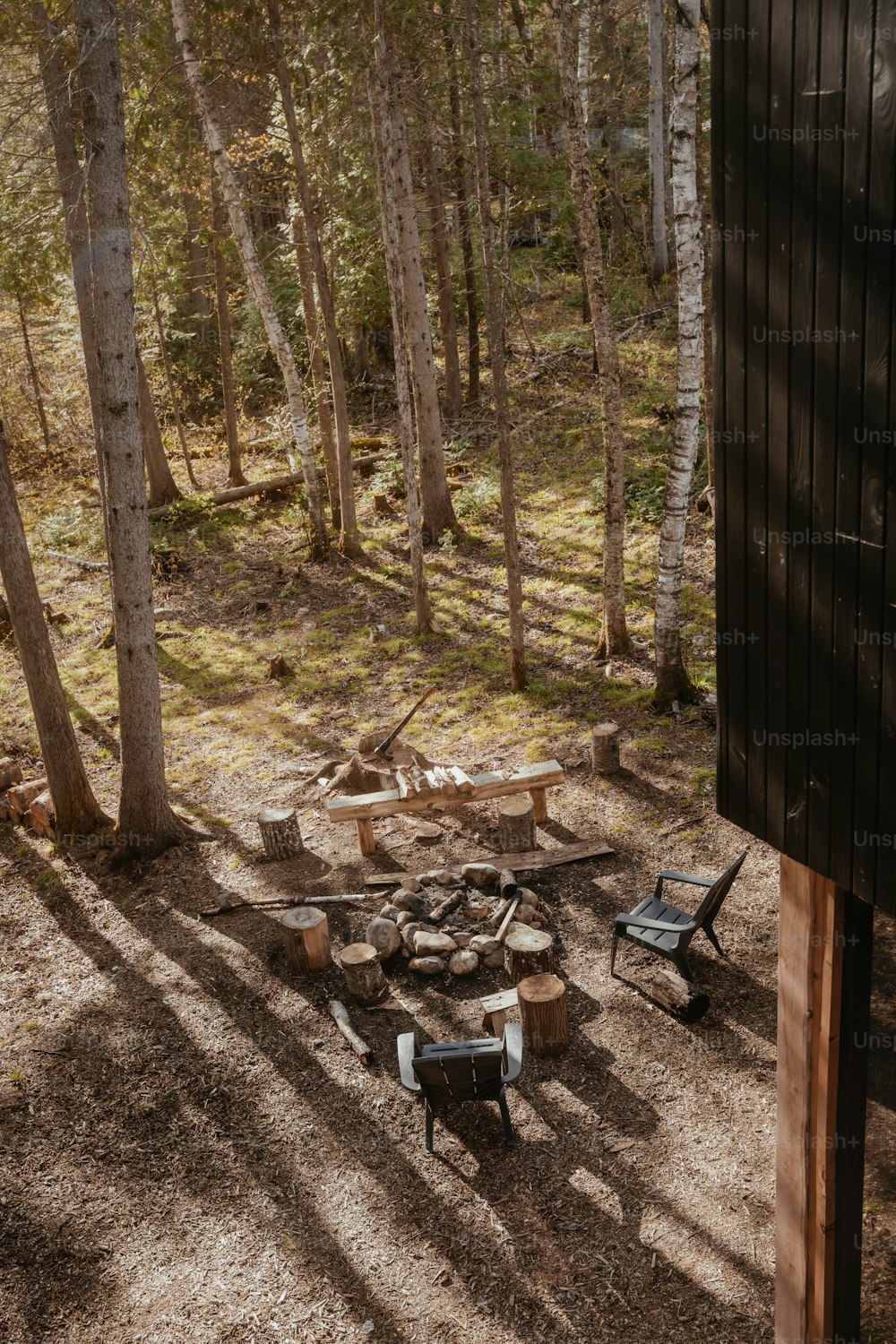 a group of chairs sitting around a fire pit in the woods