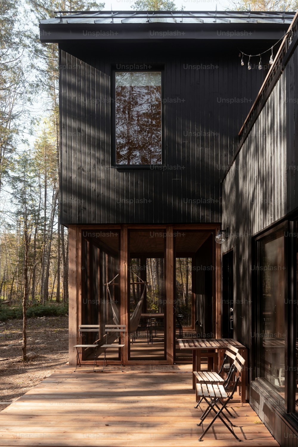a black house with a wooden deck in the woods