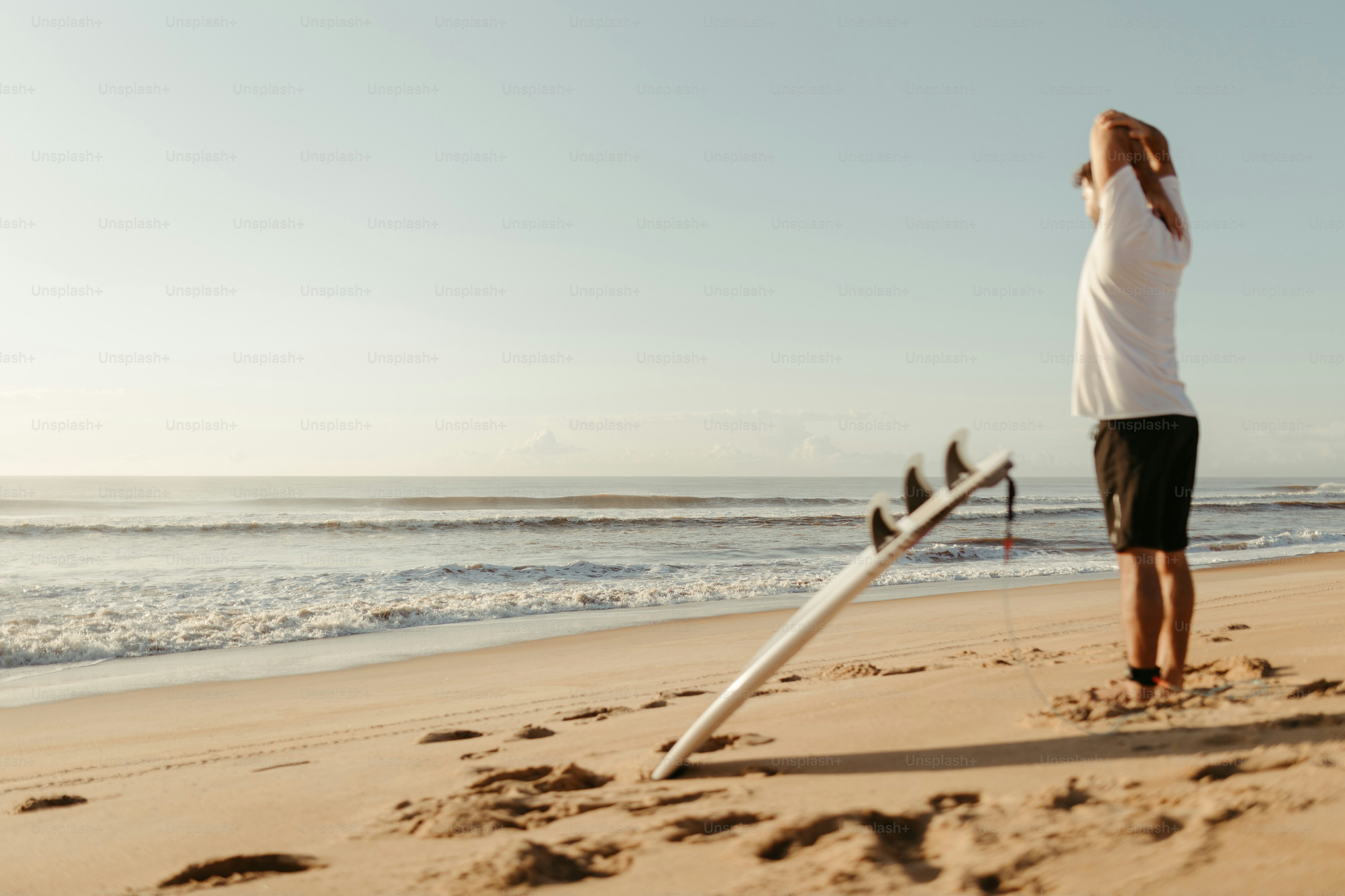 a man standing on top of a sandy beach next to the ocean