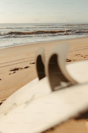 a white surfboard sitting on top of a sandy beach