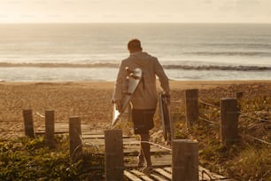 a man walking down a wooden walkway next to the ocean