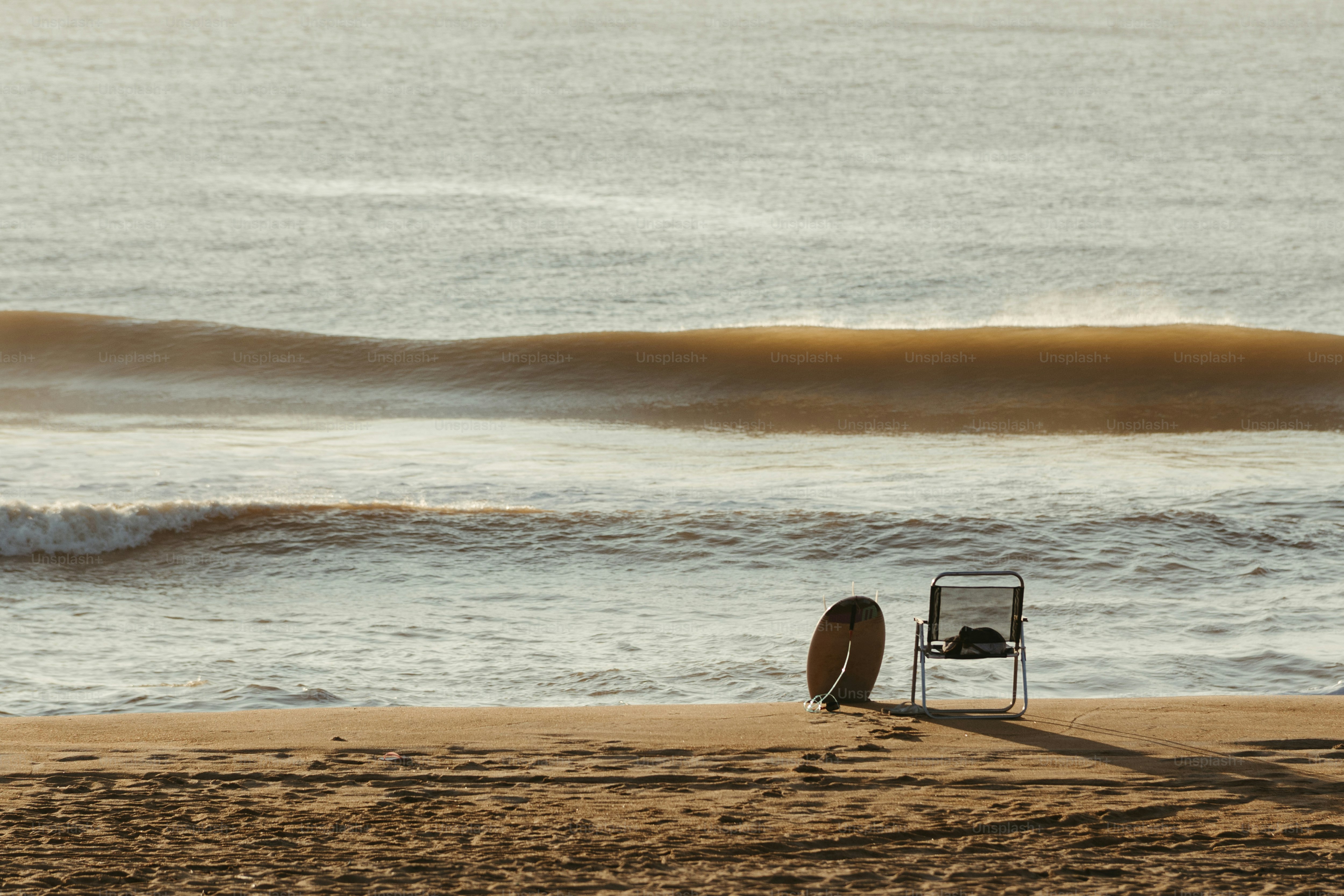 A Chair Sitting On A Beach Next To The Ocean Photo Beach Image On   Premium Photo 1684470563670 A11e9fc64a53