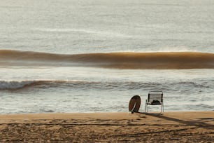 a chair sitting on a beach next to the ocean