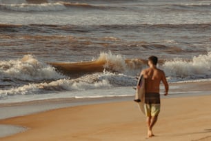 a man walking on the beach with a surfboard