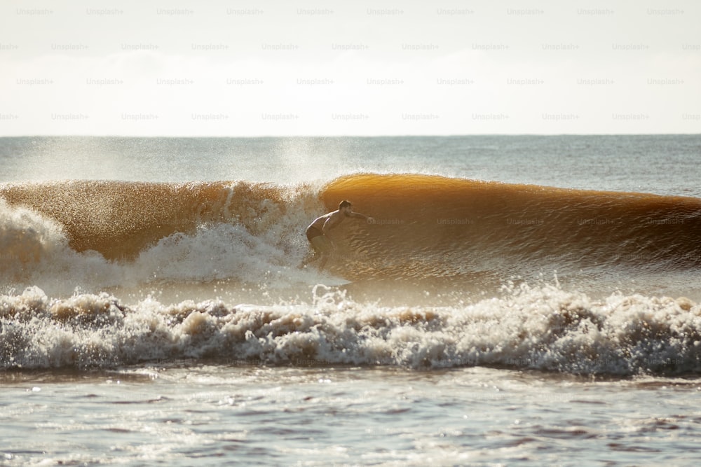 una persona montando una ola encima de una tabla de surf