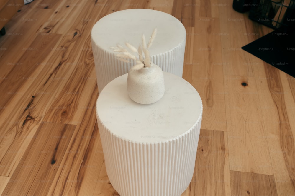 ein paar weiße Vasen, die auf einem Holzboden stehen