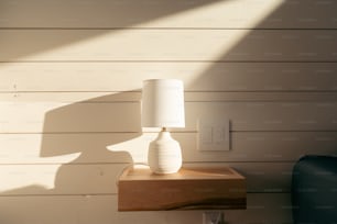 a white lamp sitting on top of a wooden table