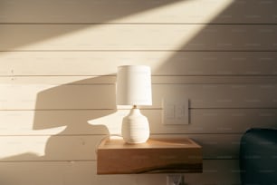 una lampada bianca seduta sopra un tavolo di legno
