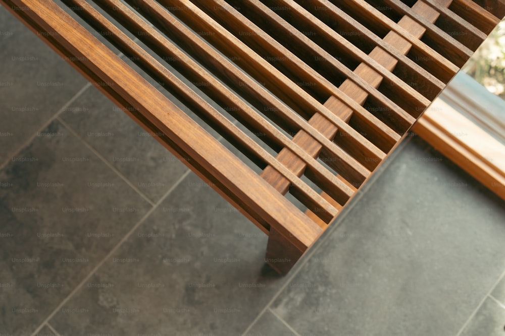 a close up of a wooden bench on a tile floor