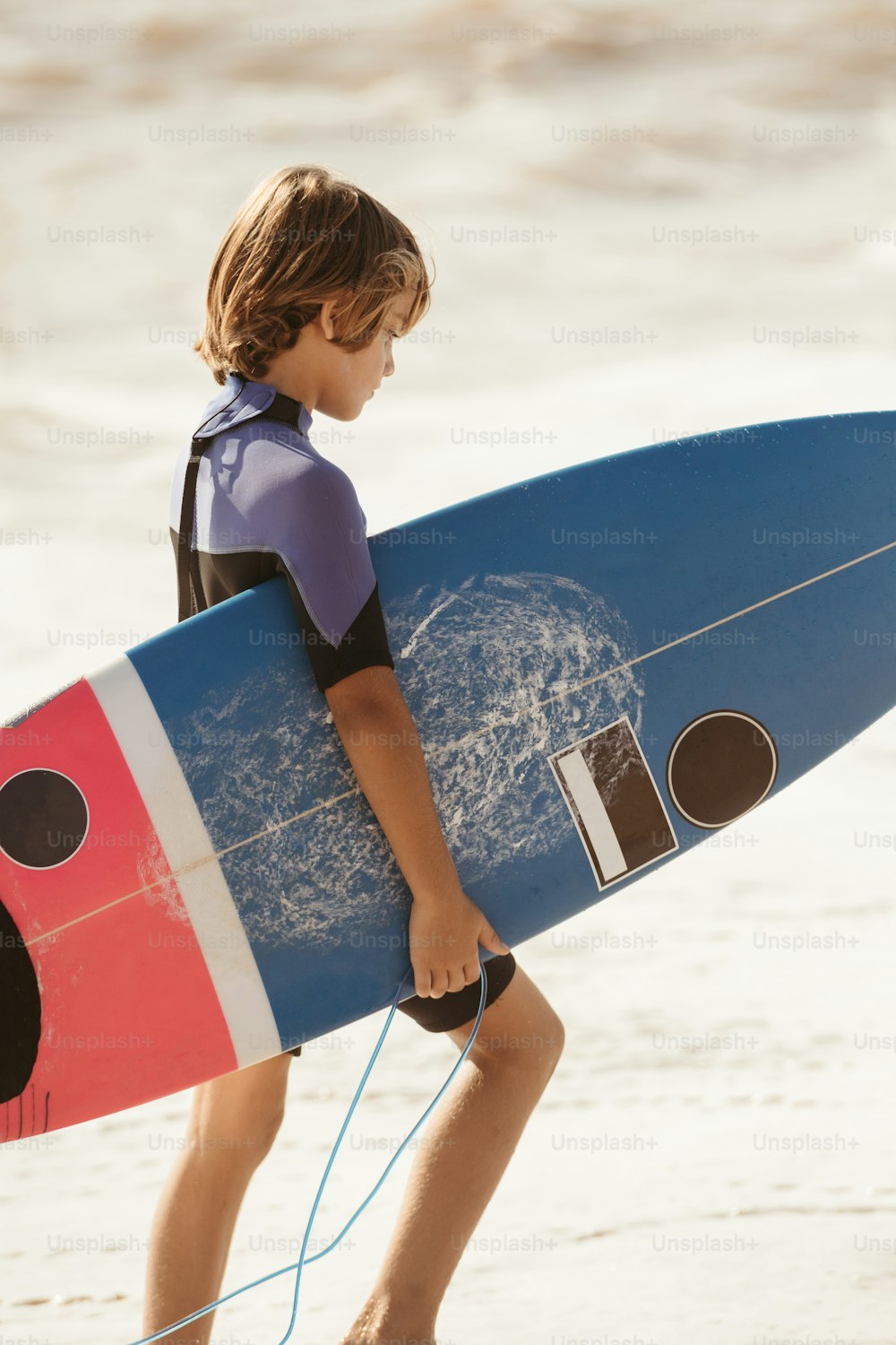 Un niño cargando una tabla de surf en la playa