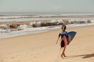 Una persona caminando en una playa con una tabla de surf