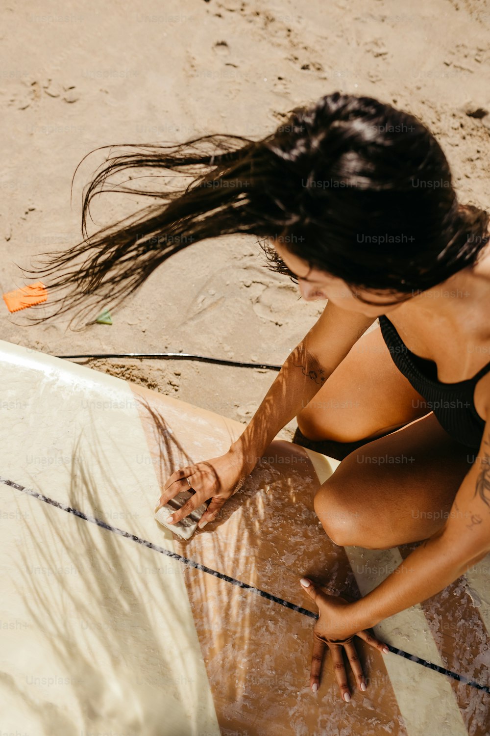 a woman sitting on a surfboard in the sand