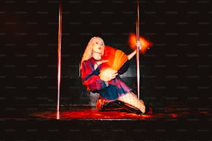 uma mulher sentada em um palco segurando um ventilador