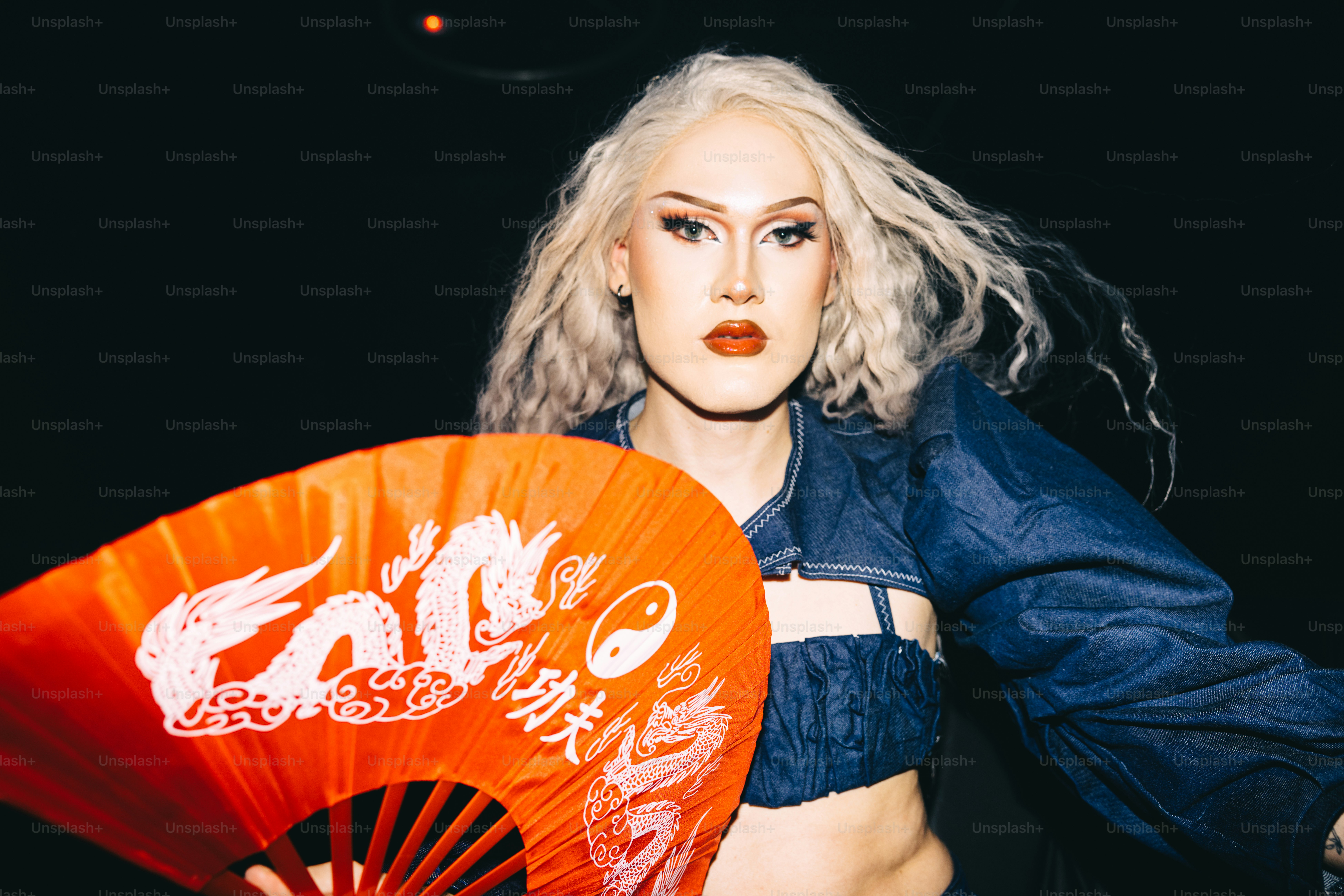 uma mulher com cabelo branco segurando um ventilador laranja