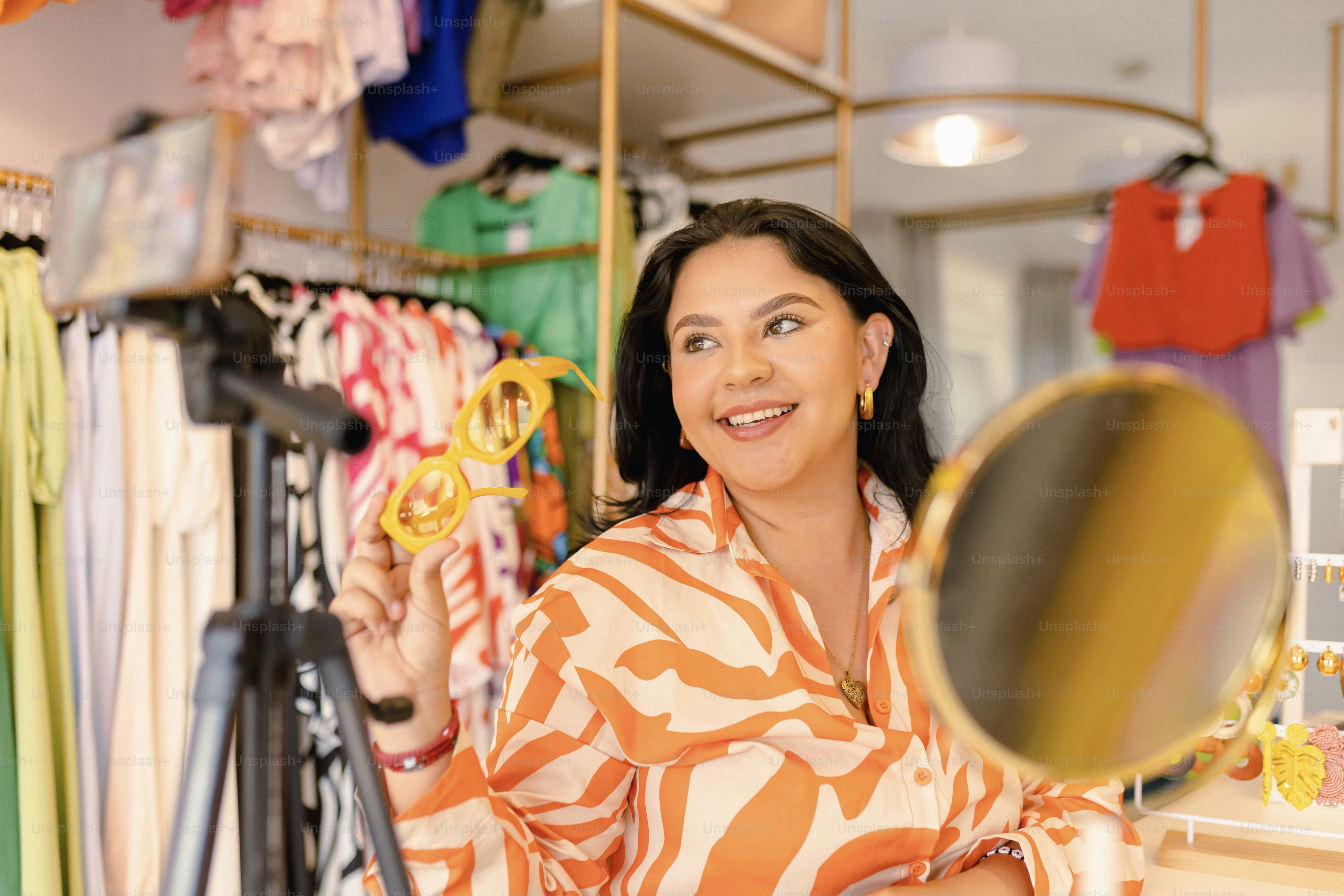 a woman holding a mirror in front of a rack of clothes