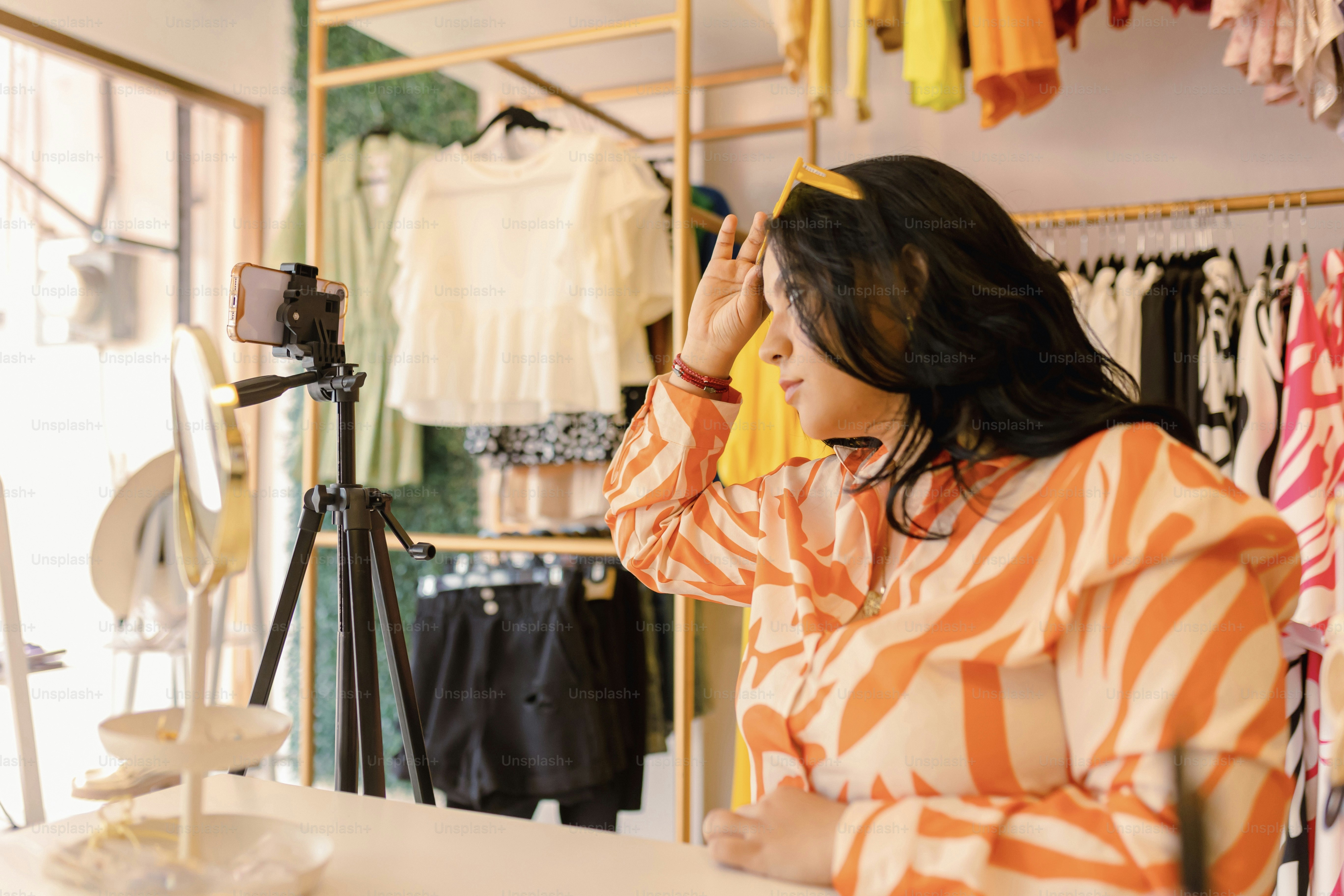 a woman in an orange and white striped shirt looking at clothes