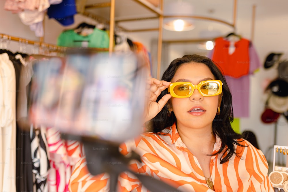 a woman wearing yellow sunglasses looking at herself in the mirror