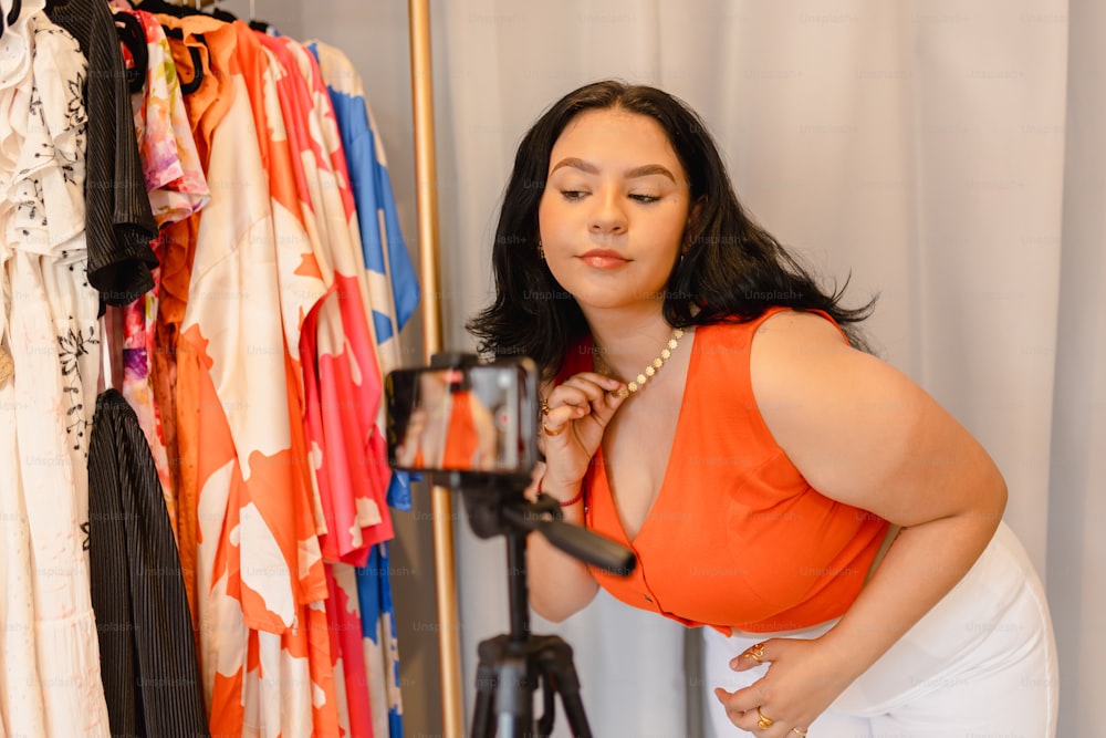 a woman taking a picture of herself in front of a rack of clothes