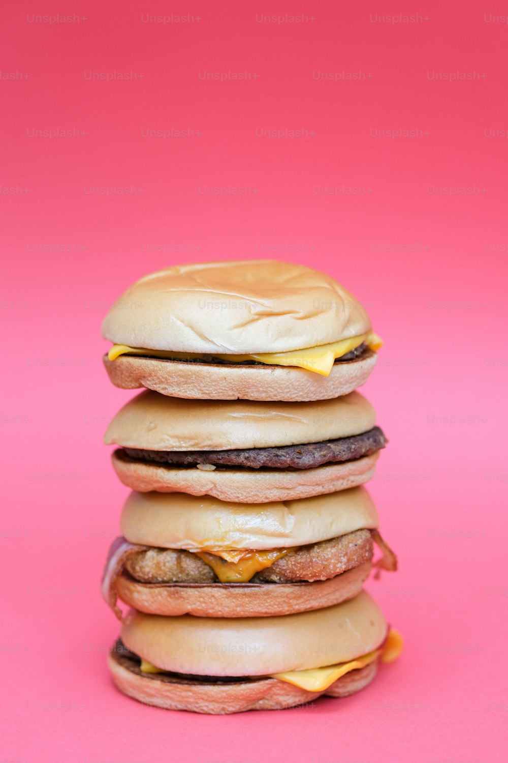 Ein Stapel Hamburger auf rosa Hintergrund