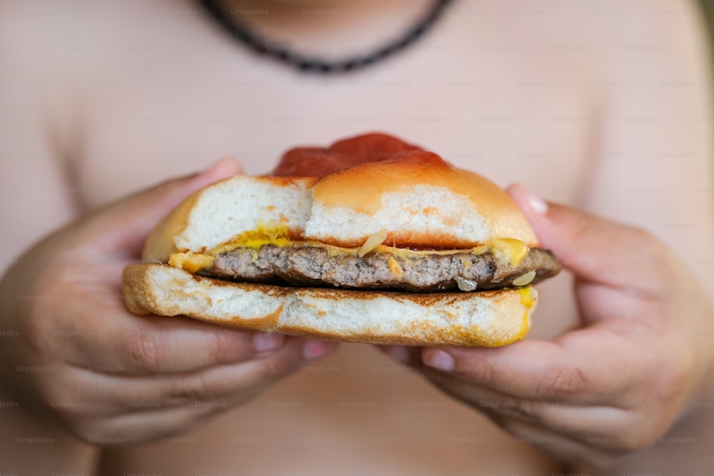 una persona sosteniendo una hamburguesa en sus manos