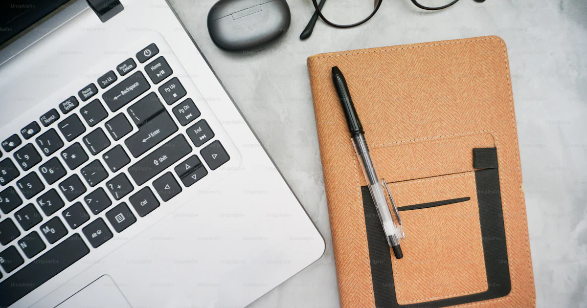A notebook with a pen, glasses, eyeglasses and a laptop on a photo ...