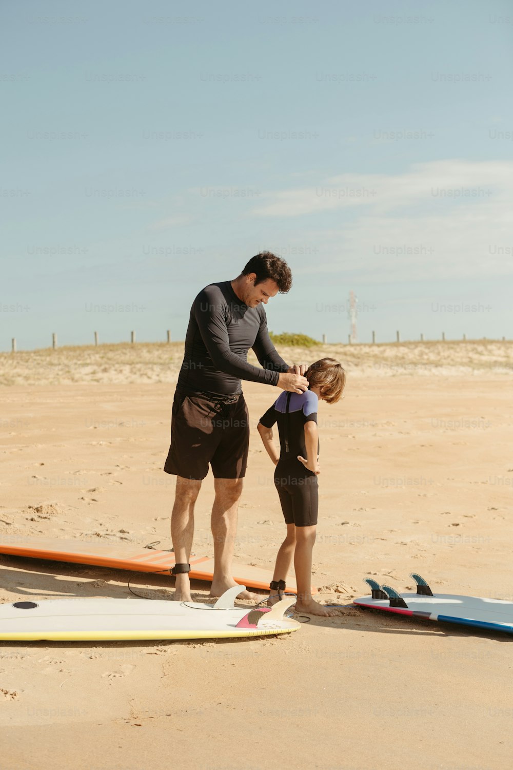 a man and a little girl standing on a beach next to surfboards