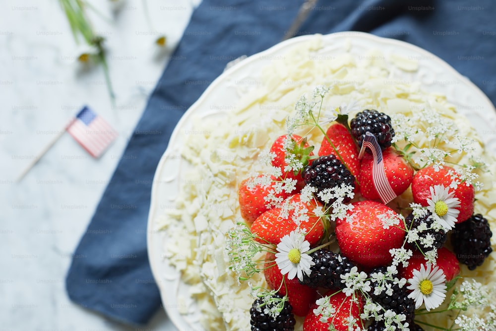 a cake with strawberries, blackberries, and daisies on it