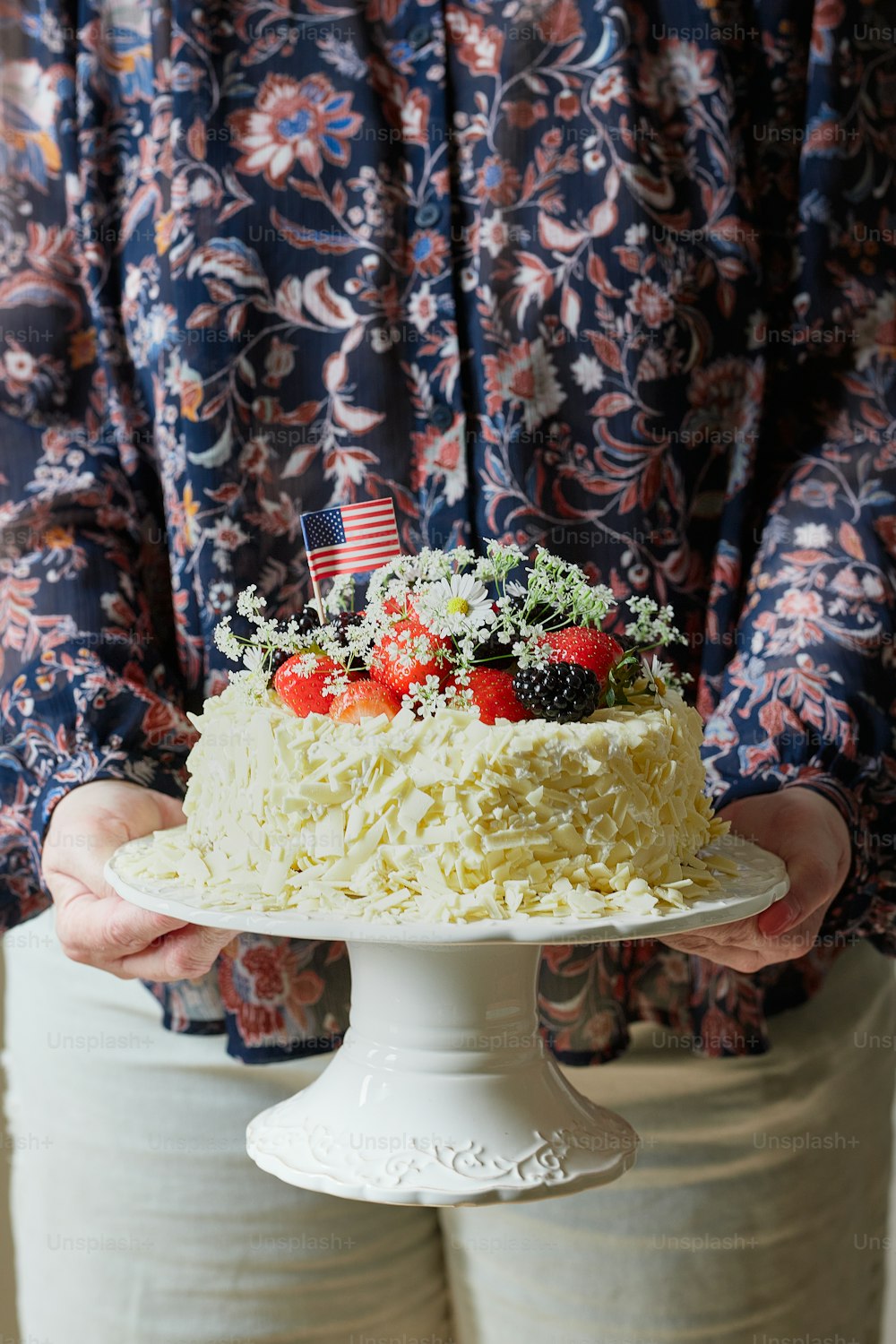 a person holding a cake with strawberries on top