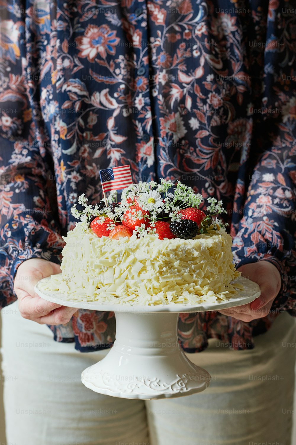 Una persona sosteniendo un pastel con fresas en la parte superior