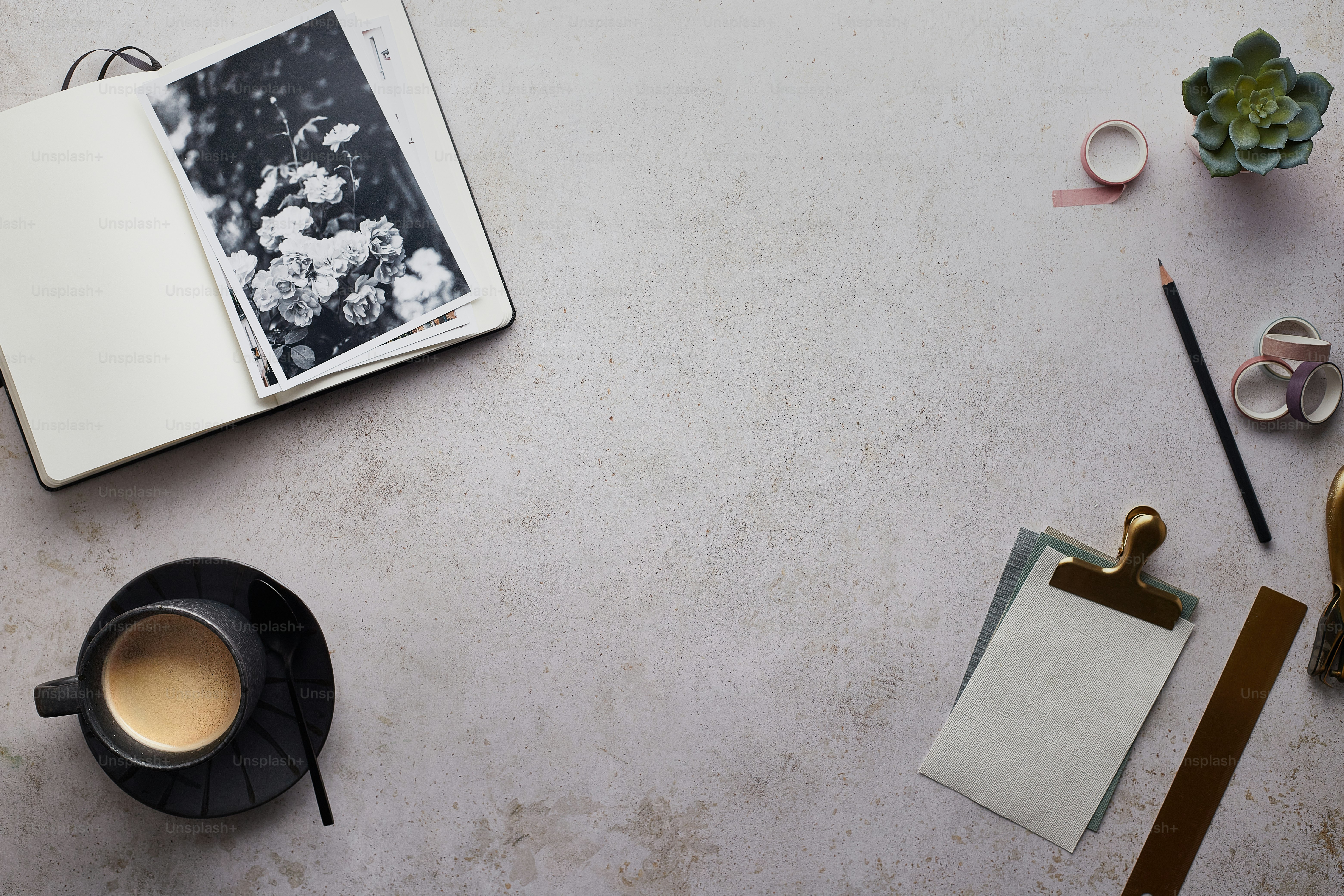 Desk essentials with notebook, ruler, pencil and tape with a cup of coffee on surface.