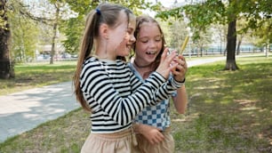 two young girls standing next to each other in a park