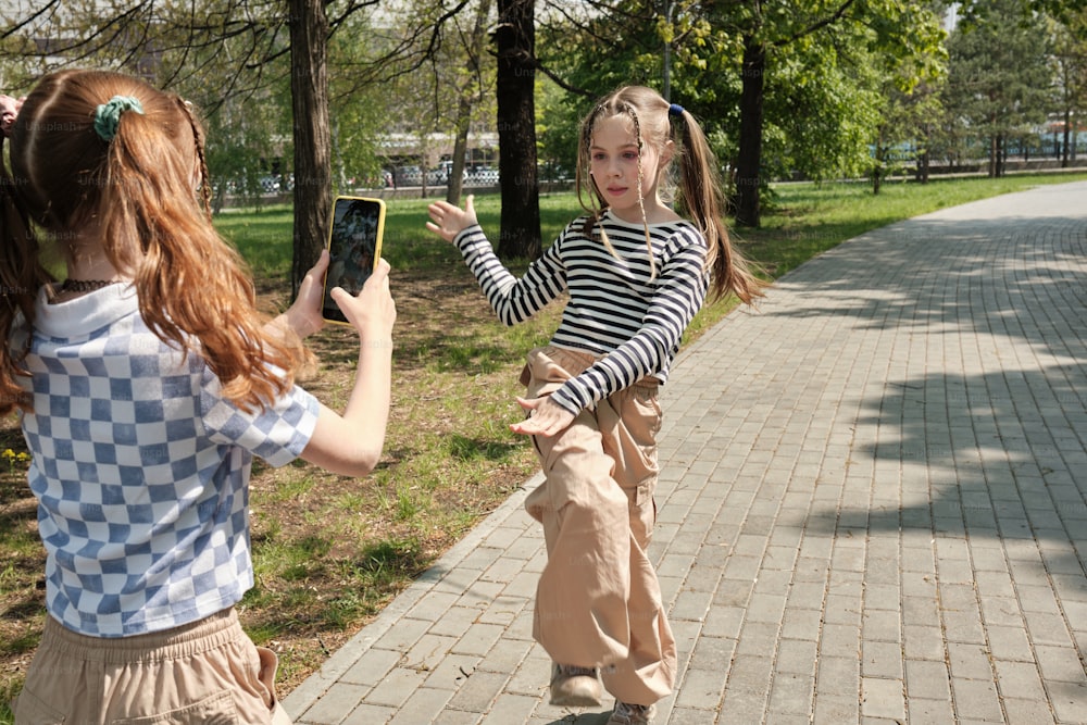 two young girls are playing with a cell phone