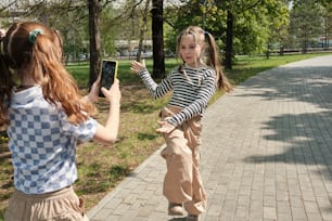 two young girls are playing with a cell phone