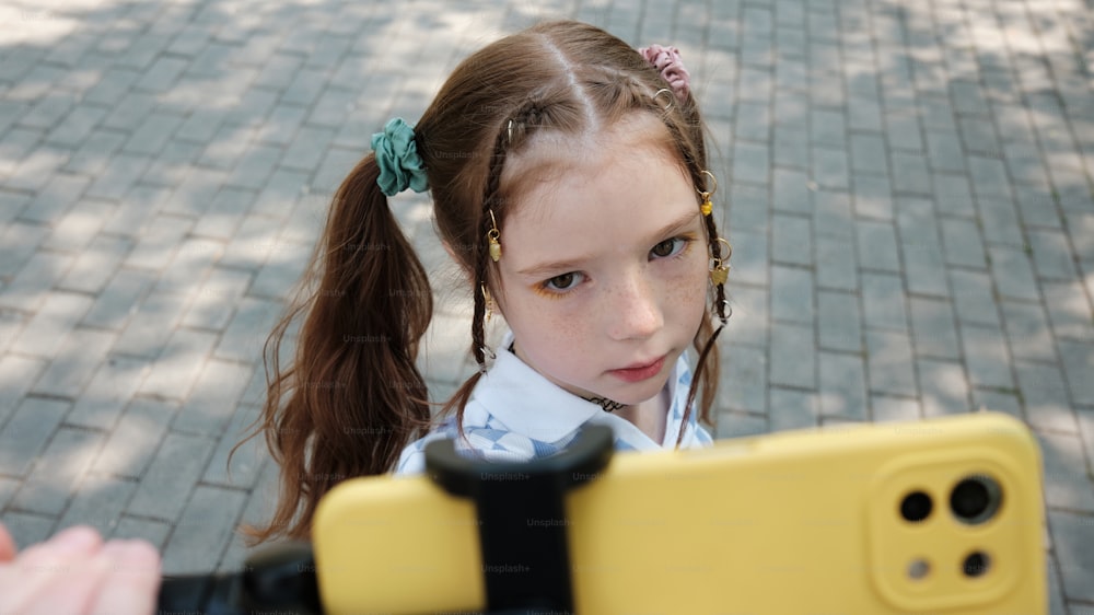 uma menina segurando um telefone celular amarelo