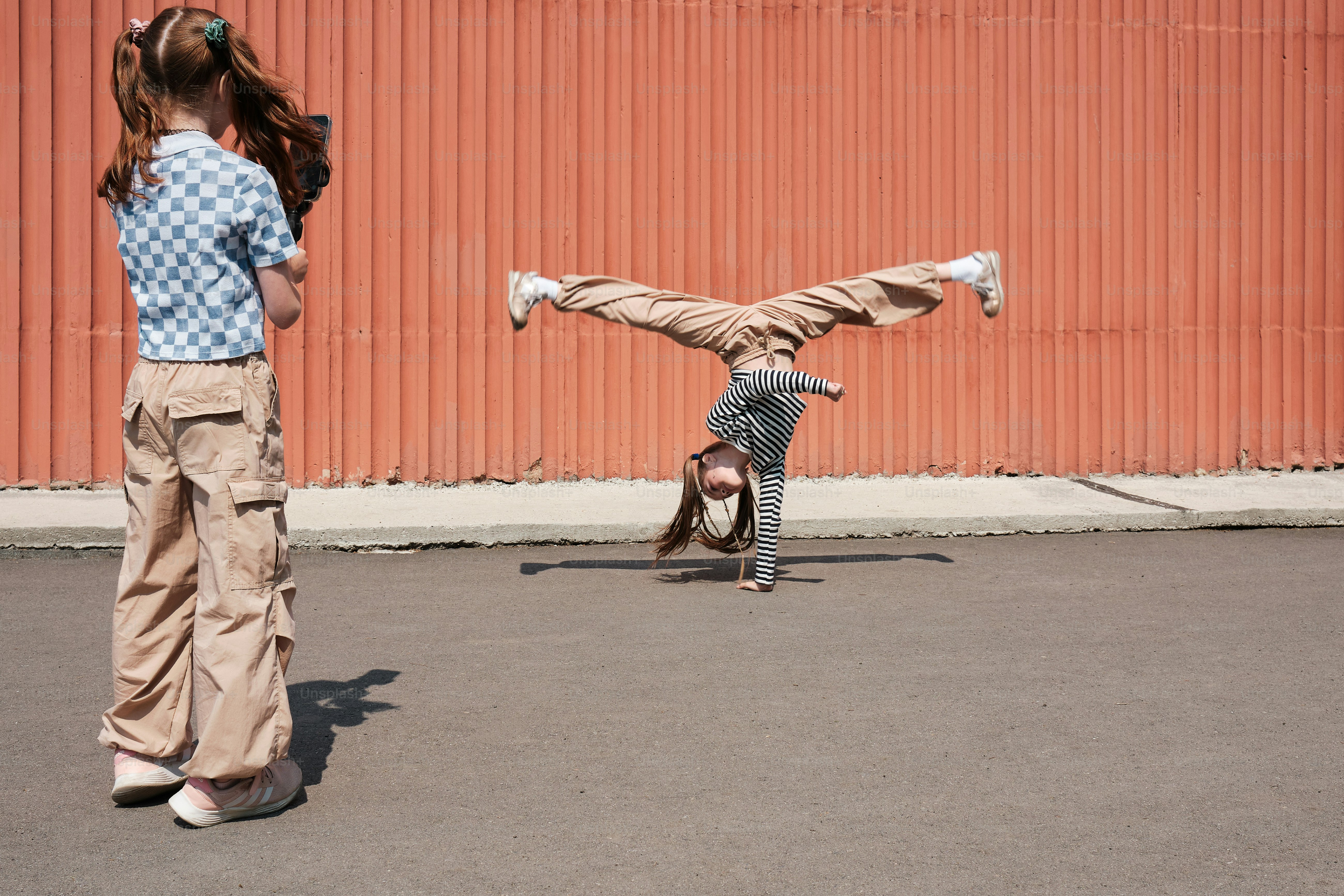 Una bambina che fa una posizione verticale su uno skateboard