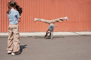 a little girl doing a handstand on a skateboard