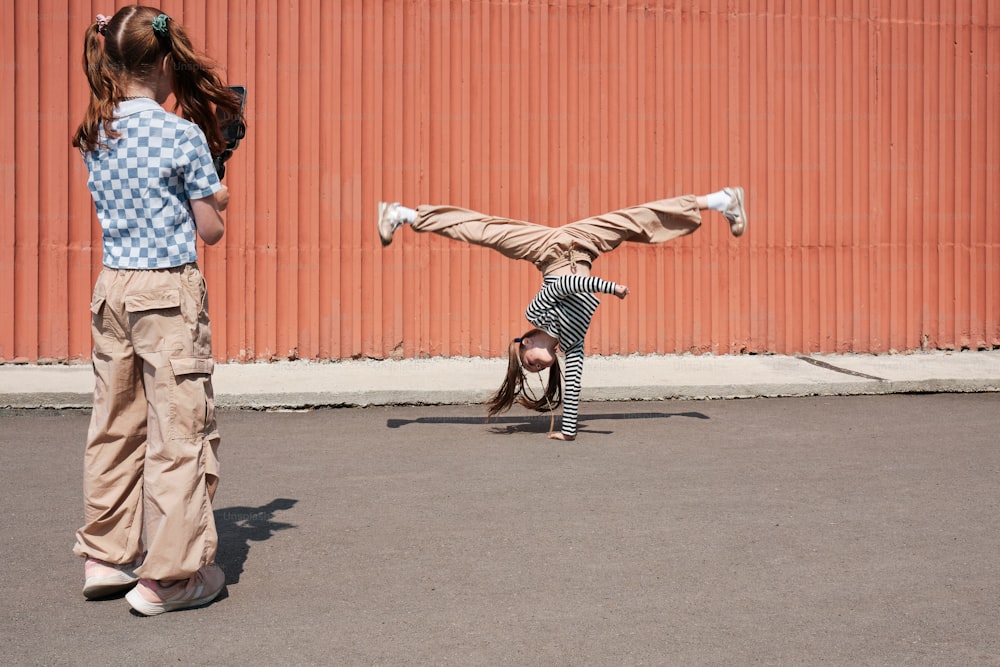 a little girl doing a handstand on a skateboard