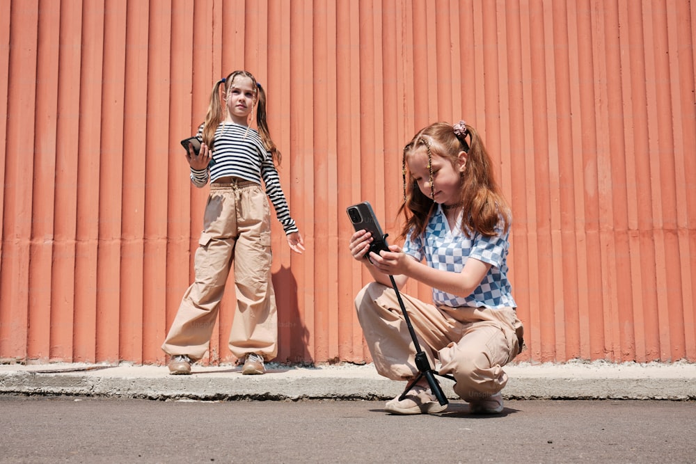 Una mujer arrodillada junto a una niña que sostiene un teléfono celular