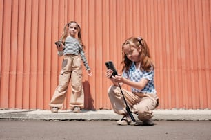 a woman kneeling down next to a girl holding a cell phone