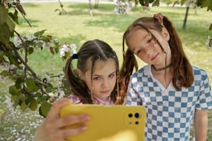 two young girls are looking at a cell phone