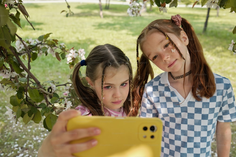 two young girls are looking at a cell phone